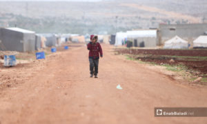طفل يمشي مواجهًا الريح في مخيمات الدانا - 15 كانون الأول 2020 (عنب بلدي/ يوسف غريبي)