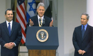 الرئيس الأمريكي بيل كلينتون يرحب برئيس الوزراء الإسرائيلي إيهود باراك (إلى اليسار) ووزير الخارجية السوري فاروق الشرع (يمين) في حديقة الورود بالبيت الأبيض في واشنطن العاصمة في 15 من كانون الأول 1999 عند استئناف محادثات السلام السورية الإسرائيلية (فرانس برس)