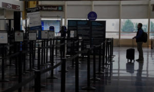 مسافر في أسبوع عيد الميلاد يقف عند بوابة أمنية في مطار رونالد ريجان واشنطن الوطني في فيرجينيا الأمريكية، 22 كانون الاول 2020 (رويترز)