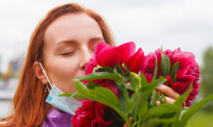 صورة تعبيرية لامرأة تستنشق رائحة الزهور زترتدي كمامة(إنترنت)