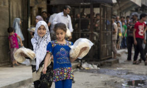 فتاتان تحملان ربطتي خبز من أمام أحد الأفران (AFP)