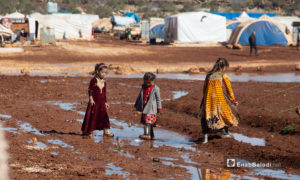 أطفال يقفون بالقرب من خيامهم بعد عاصفة مطرية ضربت مخيم كفرعورق في ريف إدلب - 31 كانون الثاني 2021 (عنب بلدي - إياد أبو الجود)