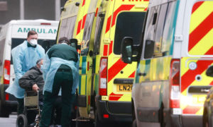 مسعفون يساعدون مريضًا في الخروج من سيارة إسعاف في مستشفى لندن الملكي، وسط تفشي فيروس كورونا، 5 كانون الثاني 2021 (رويترز)

