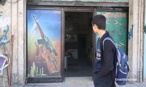 شاب يمر من أمام متجر للسلاح في مدينة إدلب - 14 من شباط 2021 (عنب بلدي/ يوسف غريبي)
