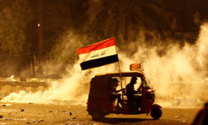 تك تك استخدمه متظاهرون عراقيون لنيقل الجرحى يسير وسط دخان ناجم عن اشتباكات مع قوى الأمن (رويترز)