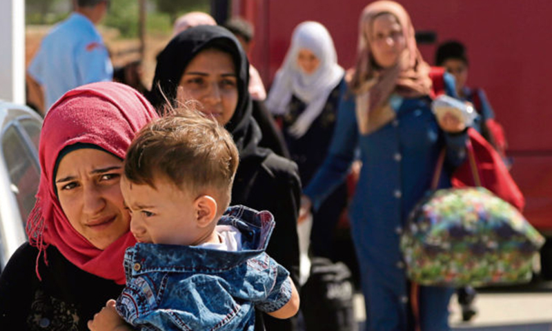نساء وطفل لاجئ من سوريا يسيران باتجاه مخيم للاجئين في كوكينوتريميثيا، خارج العاصمة نيقوسيا، في جزيرة قبرص شرق البحر المتوسط - 10 أيلول 2017 (AP)