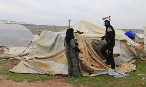 امرأة سورية تقف بجوار خيمتها التي دمرتها الرياح وتتحدث إلى عنصر من الدفاع المدني - 11 من آذار 2021 (الدفاع المدني)