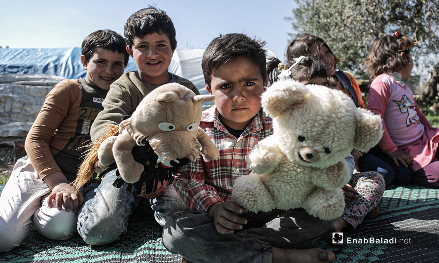 أطفال نازحون يشاهدون عرضًا للدمى المتحركة قدمته فرقة الحارة المسرحية في إحدى مخيمات النازحين قرب مدينة إدلب 28 آذار 2021 (عنب بلدي/ تصوير يوسف غريبي)