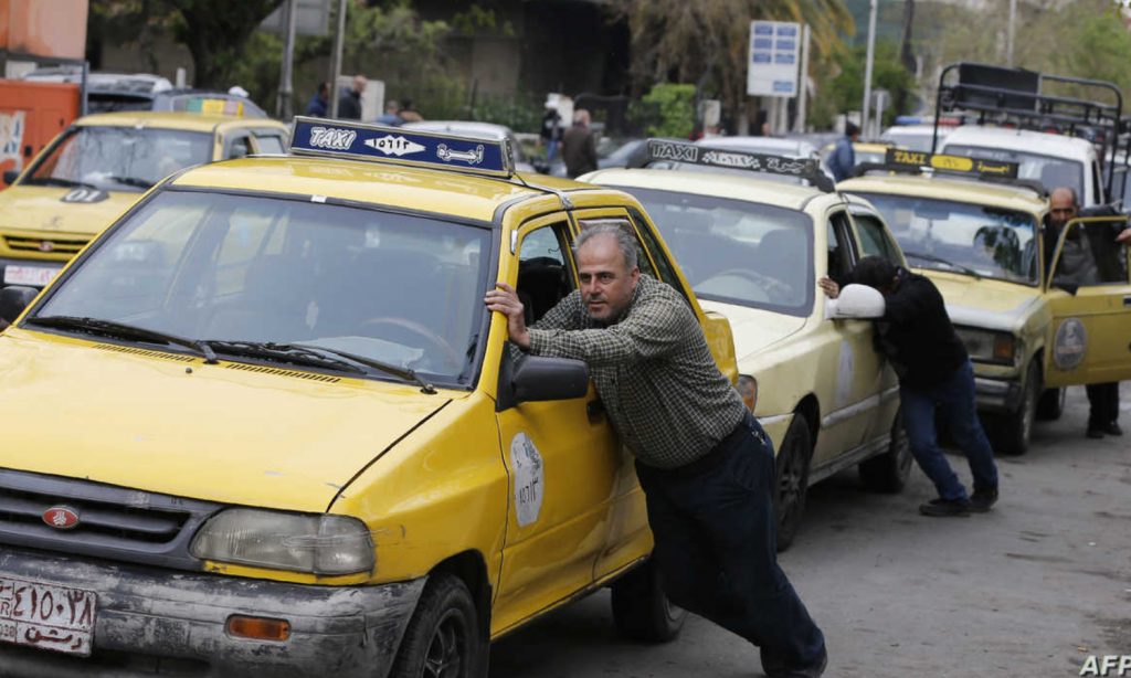مواطنون يدفعون سياراتهم بسبب أزمة الوقود في دمشق (AFP)