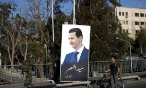 مارة بجانب ملصق للأسد معلق على جسر في  دمشق - 14 من تموز 2018  (أسوشيتد برس)