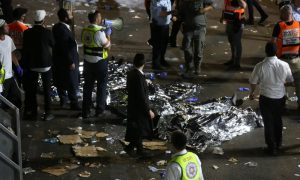 مسعفون يقفون بجانب جثث مغطاة بعد مقتل عشرات الأشخاص وإصابة آخرين إثر انهيار مدرج في إسرائيل - 30 من نيسان 2020 (ِAFP)