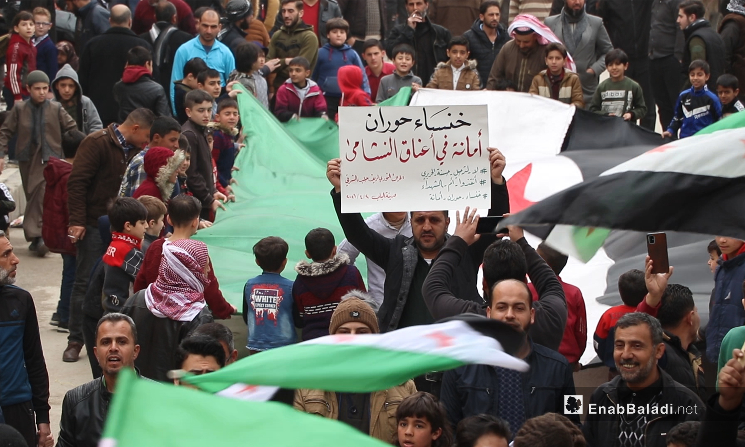 متظاهر يرفع لافتة كتب عليها شعارات رافضة لترحيل حسنة الحريري من الأردن خلال مظاهرة في مدينة الباب بريف حلب الشمالي - 2 نيسان 2021 (عنب بلدي/ عاصم الملحم)