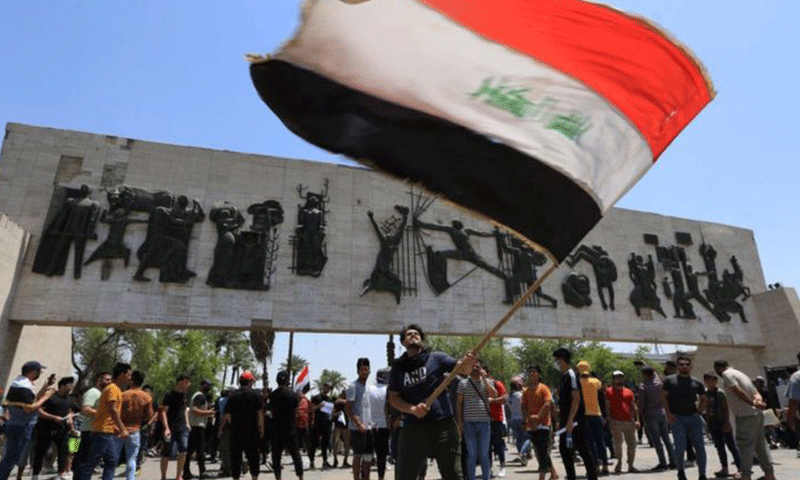 متظاهر عراقي يحمله علم بلاده في ساحة التحرير في العاصمة العراقية بغداد أثناء احتجاجات تطالب بمحاسبة المسؤولين عن اغتيال النشطاء- 25 من أيار 2021 (جيتي)