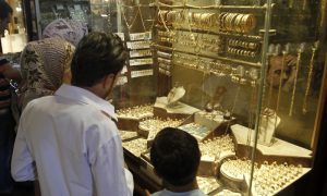 عائلة تقف أمام واجهة محل لبيع الذهب في دمشق (رويترز)