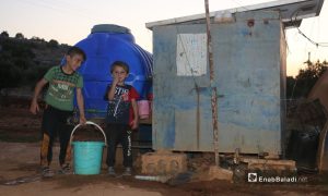 أطفال سوريون أمام إحدى خزانات المياه الأرضية في مخيم بريف إدلب الشرقي- 21 من حزيران 2021 (عنب بلدي)
