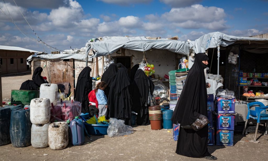 نساء من عائلات التنظيم يتسوقن داخل سوق مؤقت في مخيم "الهول" 2 من تموز. (The Guardian)