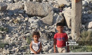 طفلان سوريان أمام مبنى مهدم في مدينة الرقة شمال شرقي سوريا- 26 من تموز 2020 (عنب بلدي/عبد العزيز الصالح)
