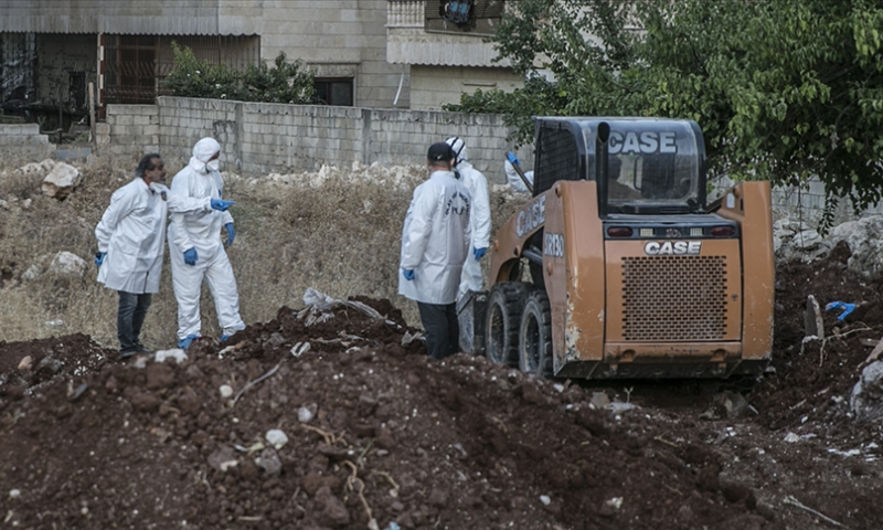 عمال أثناء عمليات حفر عثرت على جثث مجهولة الهوية في عفرين شمال غربي سوريا (الأناضول)