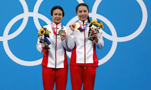 تينغماو شي وهان وانغ من فريق الصين يقفان مع الميداليات الذهبية على منصة التتويج خلال حفل توزيع الميداليات لنهائيات الوثب 3 م سيدات في اليوم الثاني من دورة الألعاب الأولمبية طوكيو 2020-  25 تموز 2021 (Al Bello/Getty Images)