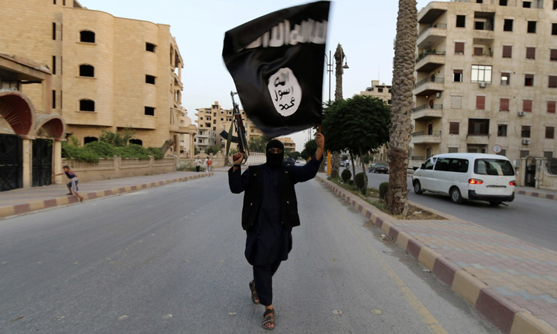 مقاتل من تنظيم الدولة الإسلامية يرفع راية التنظيم في شوارع مدينة دير الزور - (رويترز)