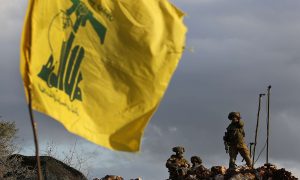 جنود إسرائيليون يقفون أمام علم حزب الله قرب قرية ميس الجبل الحدودية (AP)