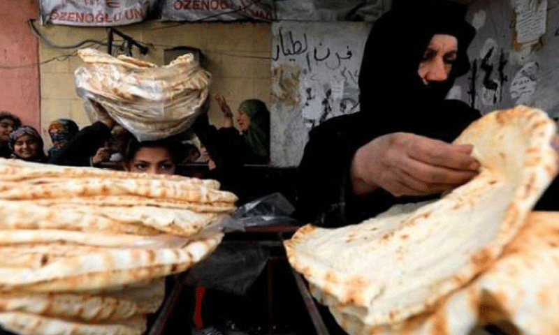 امرأة سورية تحمل أرغفة خبز أمام إحدى الأفران في شمال شرقي سوريا- 2020 (رويترز)