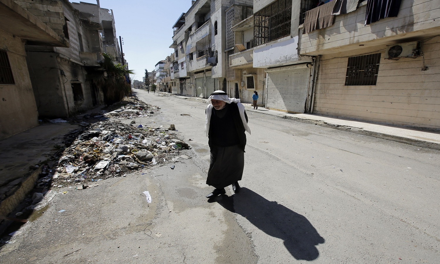 رجل مسن سوري يمشي في إحدى الأحياء السكنية في مدينة حمص بعد أن خرج منها أكثر من 2000 مدني حين انفك الحصار عنها- 12 من شباط 2015 AFP))

