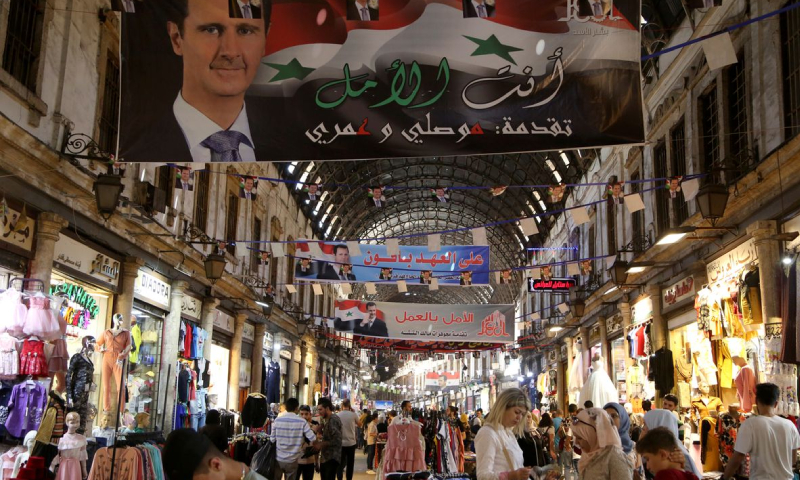 أشخاص يتسوقون في سوق الحميدية في مدينة دمشق قبيل الانتخابات الرئاسية (رويترز)