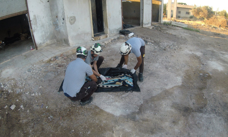 عناصر من "الدفاع المدني السوري" يغطون جثة طفل قضى بقصف للنظام على ريف إدلب الجنوبي (الدفاع المدني السوري)