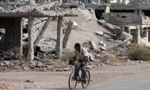 رجل سوري يقود دراجة هوائية بالقرب من أبنية مدمرة في حي تسيطر عليه فصائل المعارضة السورية في مدينة درعا جنوبي سوريا- 2 من تشرين الأول 2018 (AFP محمد أبازيد)
