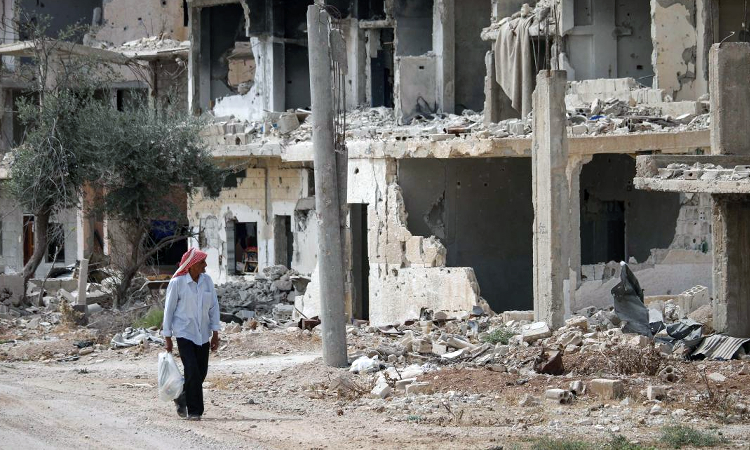 رجل سوري يمر من أمام أنقاض أبنية مدمرة في حي تسيطر عليه فصائل المعارضة بمدينة درعا جنوبي سوريا- 2 من تشرين الأول 2018 (AFP محمد أبازيد)
