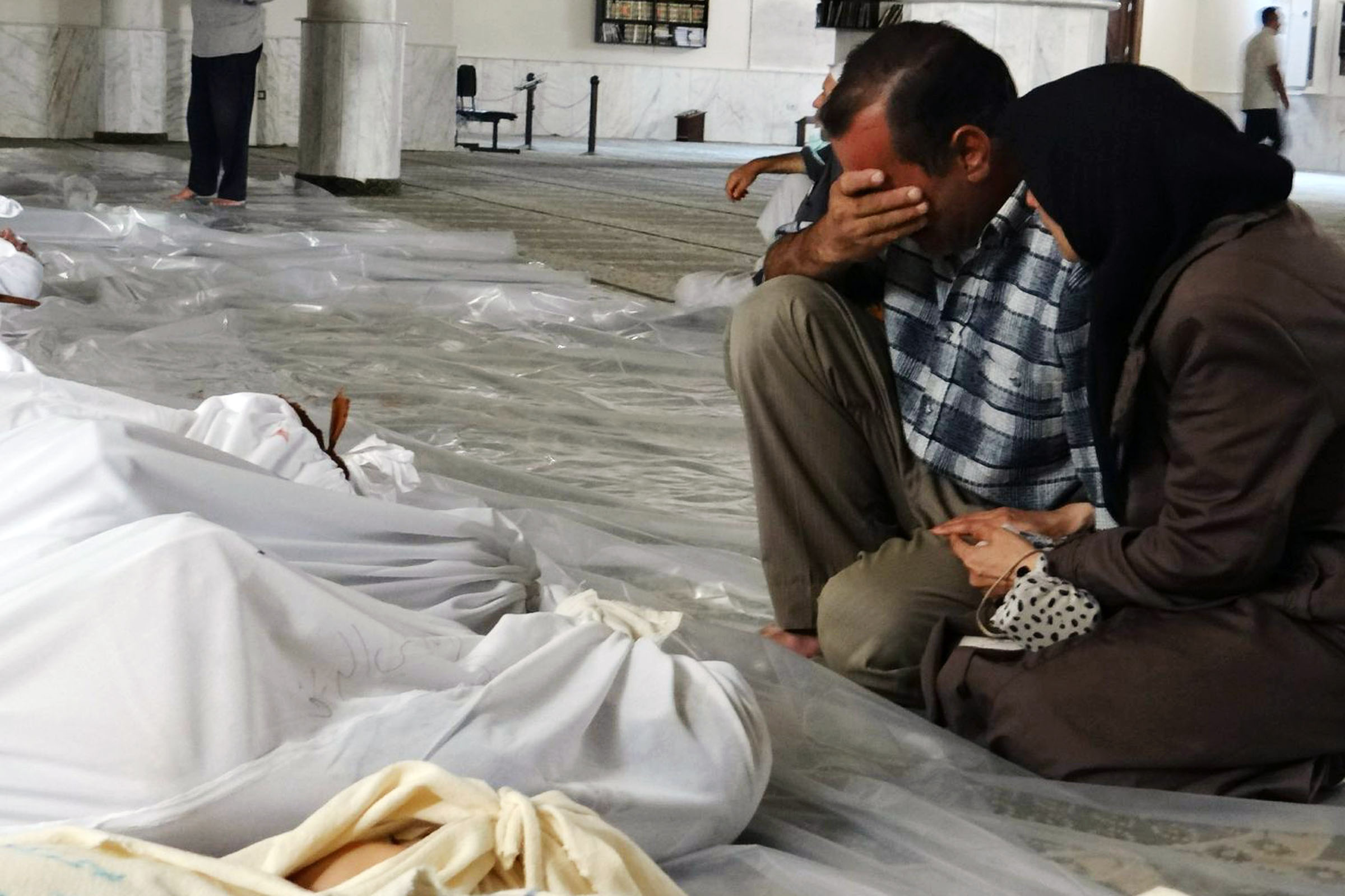 زوجان سوريان يبكيان أمام جثث مجزرة الكيماوي في غوطة دمشق الشرقية- 21 من آب 2013 (AFP)
