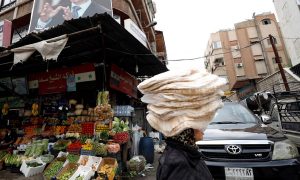 سيدة تحمل ربطات من الخبز في دمشق (رويترز)