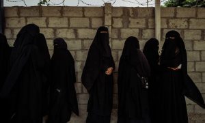 نساء ينتظرن خارج مكتب إداري في مخيم الهول، الذي يضم أفراد عائلات مقاتلي 