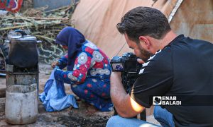 إعلامي يقوم بتصوير أمرأة مهجرة في مخيم السكة في بلدة حربنوش - 18 أيلول 2021 (عنب بلدي - إياد عبد الجواد)
