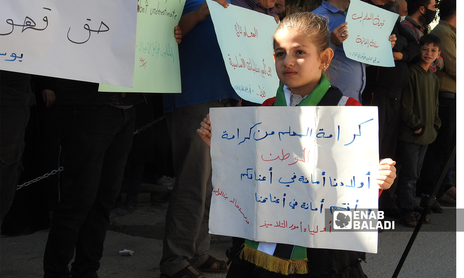 طفلة تحمل لافتة كتب عليها "كرامة المعلم من كرامة المواطن "  في مدينة اعزاز بريف حلب 21 تشرين الأول 2021 (عنب بلدي - وليد عثمان)