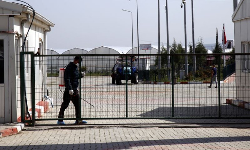 عامل يعقّم بوابة مركز لإعادة اللاجئين تابع لوزارة الداخلية التركية (الأناضول)