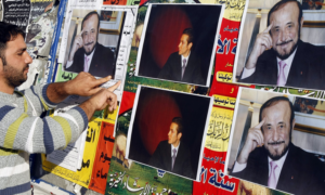 أحد أفراد المجتمع العلوي يلصق صور رفعت الأسد على جدار في مدينة طرابلس شمال لبنان، كانون الأول 2007 (وكالة الصحافة الفرنسية)
