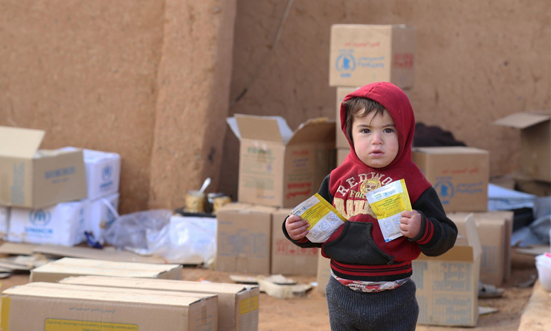 طفل في سوريا يحمل مساعدات غذائية من "برنامج الأغذية العالمي" (WFP)