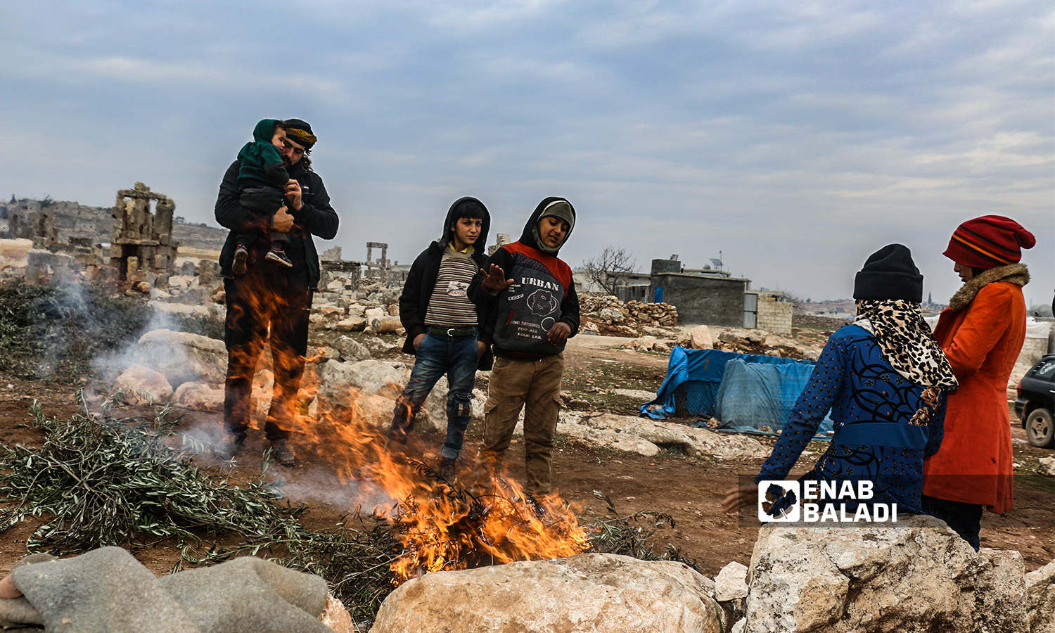 مهجرون سوريون يشعلون نار للتدفئة  في منطقة سرجبلة الأثرية في ريف إدلب الشمالي- 22 كانون الثاني 2022 (عنب بلدي / إياد عبد الجواد)
