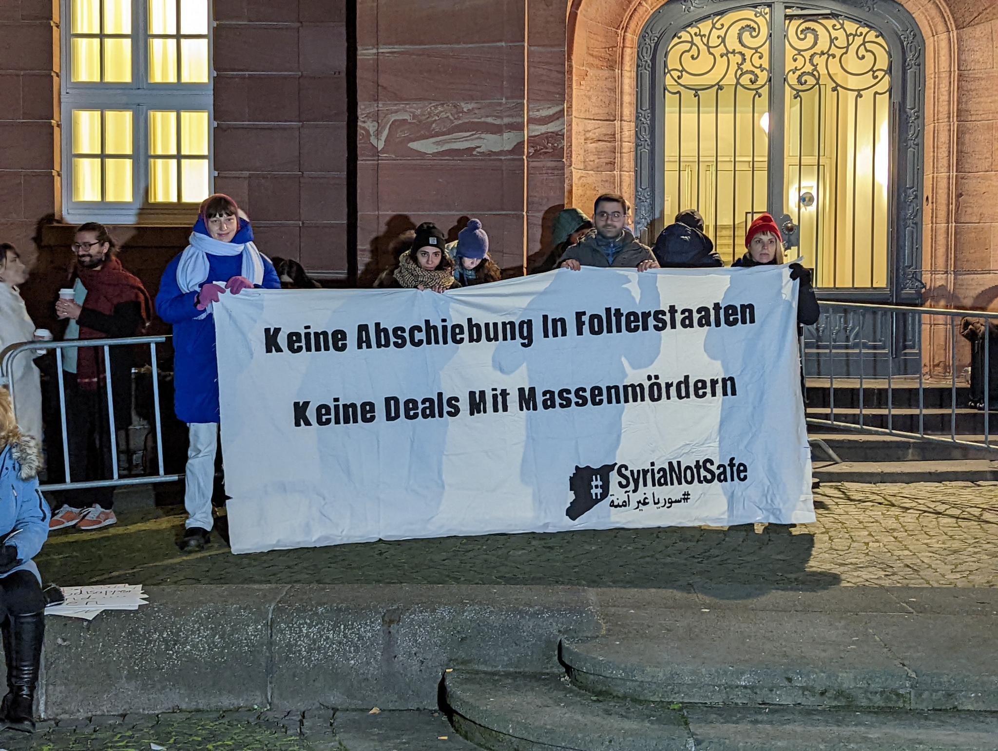 سوريون أمام مبنى المحكمة العليا في بلدة كوبلنز غربي ألمانيا يحملون لافتة ترفض فكرة ترجيل اللاجئين السوريين من دول أوروبا والتطبيع مع النظام السوري- 13 من كانون الثاني 2022 (Adopt a Revolution)