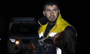 المتطوع في الدفاع المدني علاء هواش يحمل طفلة قتلت بغارة جوية روسية استهدفت نازحين قرب جسر الشغور غربي إدلب في الساعات الأولى من عام 2022 (الدفاع المدني)
