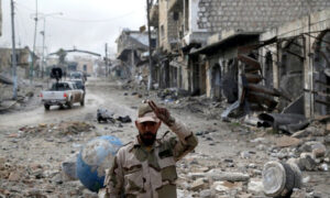 جندي بقوات النظام السوري في إحدى المدن السورية المدمرة (رويترز)