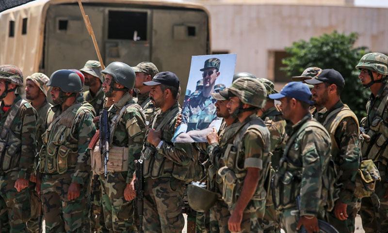 جنود سوريون يحملون صورة رئيس النظام السوري بشار الأسد في محافظة درعا الجنوبية لسوريا- 7 من تموز 2018 (AP)