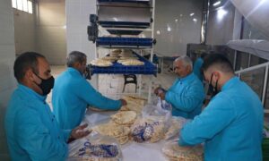 عمال يعبئون الخبز في أكياس النايلون داخل مخبز 
