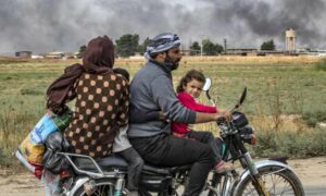 أفراد عائلة سورية يستخدمون دراجة نارية للفرار من رأس العين باتجاه تل تمر في الحسكة _19 تشرين الأول 2019 (Delil Souleiman/AFP)