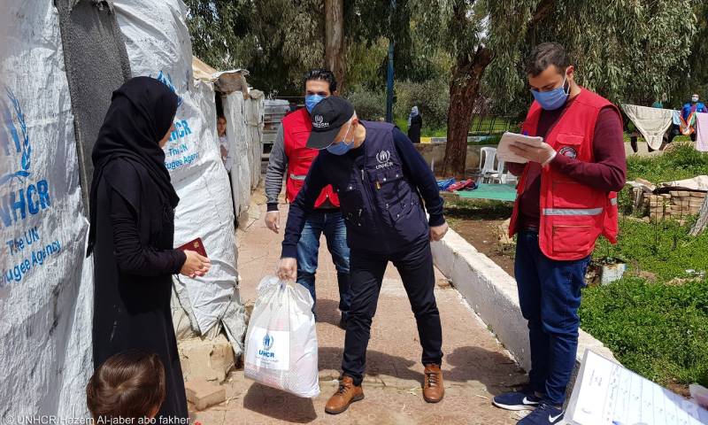 عاملون في "الهلال الأحمر" السوري و"UNHCR" يوزعون مستلزمات النظافة الشخصية لعائلات النازحة في مركز إيواء في قرية رساس جنوب سوريا- 21 نيسان 2021 (UNHCR)