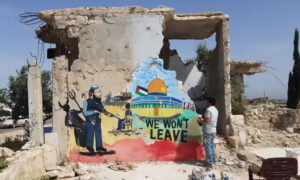 الرسام عزيز الأسمر أمام إحدى جدارياته التي تجسد قبة الصخرة تضامنًا مع فلسطين (الجزيرة)
