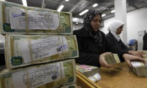 موظفون يحصون مبالغ من العملة السورية في مصرف 