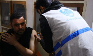 متطوع من فريق الدفاع المدني السوري أثناء تلقيه جرعة من لقاح فيروس كورونا (الدفاع المدني السوري/ تيلجرام)